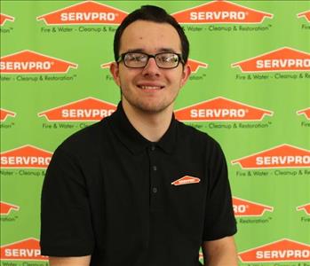 image of male employee sitting in front of SERVPRO backdrop