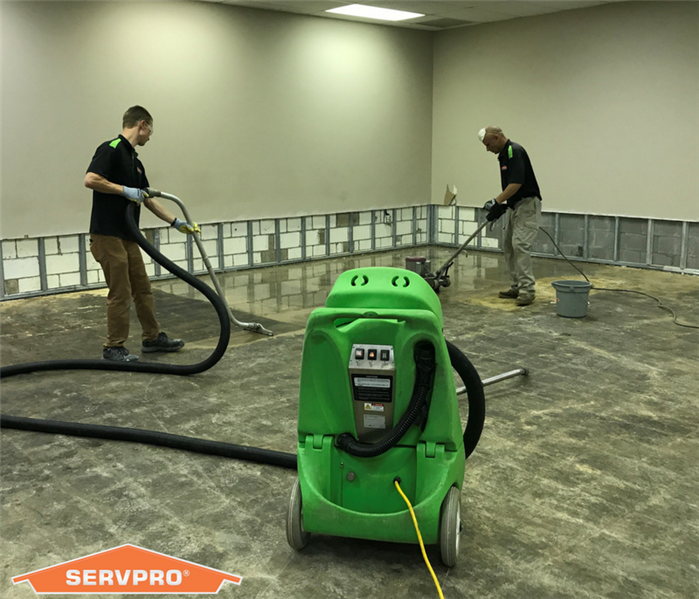 SERVPRO team members extract water from a floor.