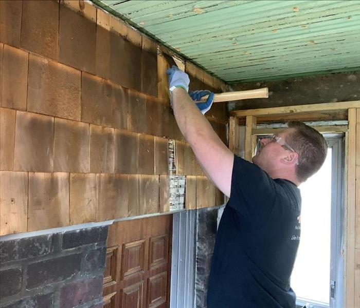 SERVPRO team member is working on a wall damaged by a fire.