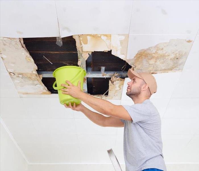 image of homeowner catching leaking roof with a bucket